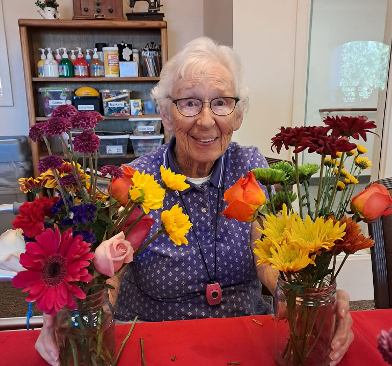 a person holding a vase of flowers on a table